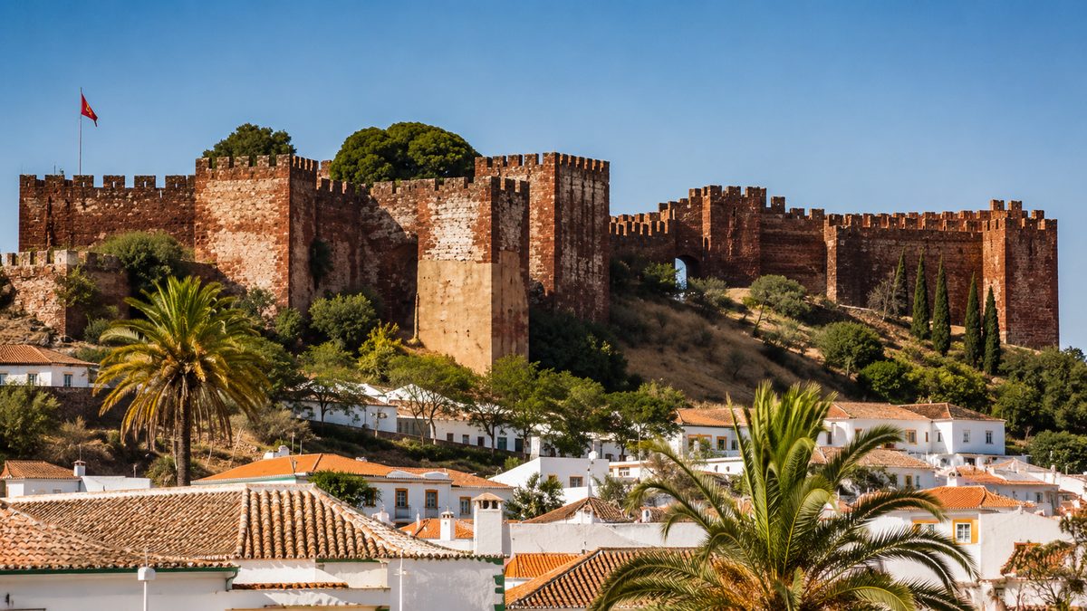 The red sandstone walls and towers of Castelo de Silves rising above the whitewashed town, Algarve