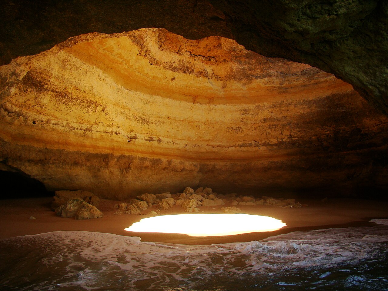 Inside the Benagil cave in the Algarve with its round skylight, golden rock and sea water
